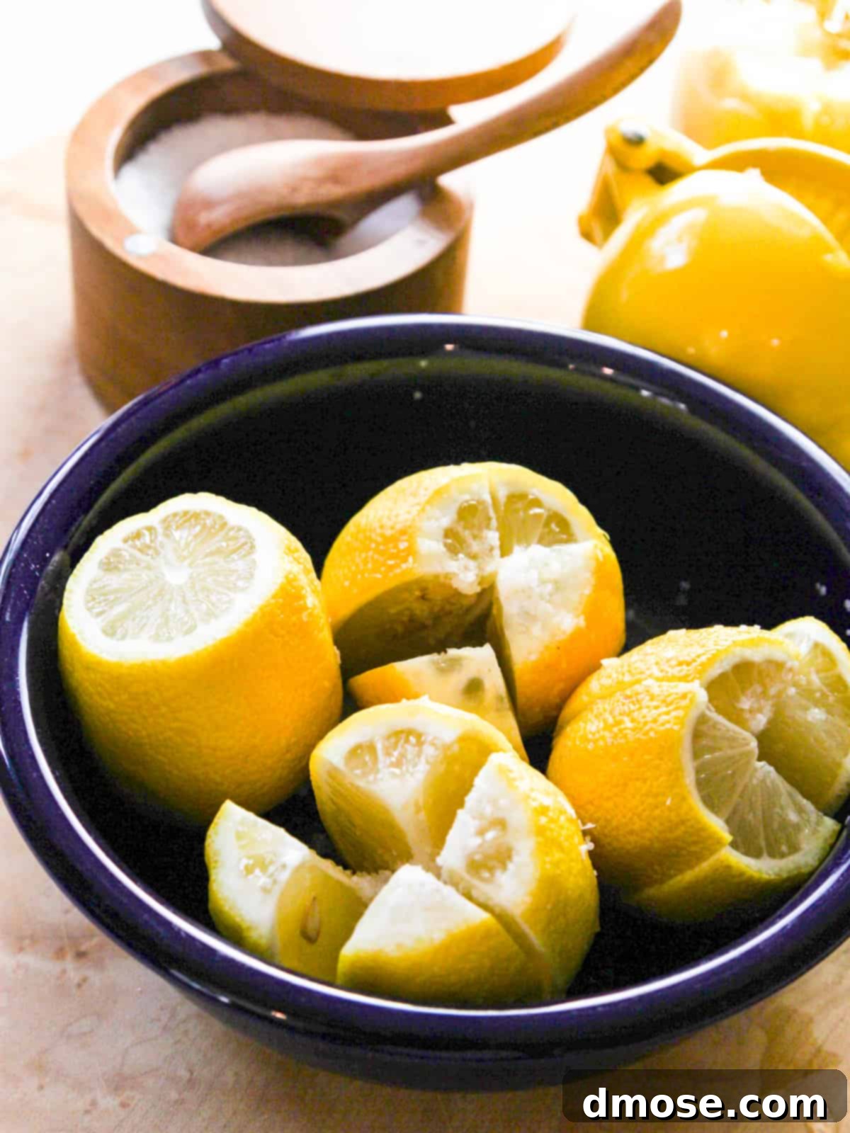 Cut lemons in a blue bowl sliced and salted to make preserved lemons.
