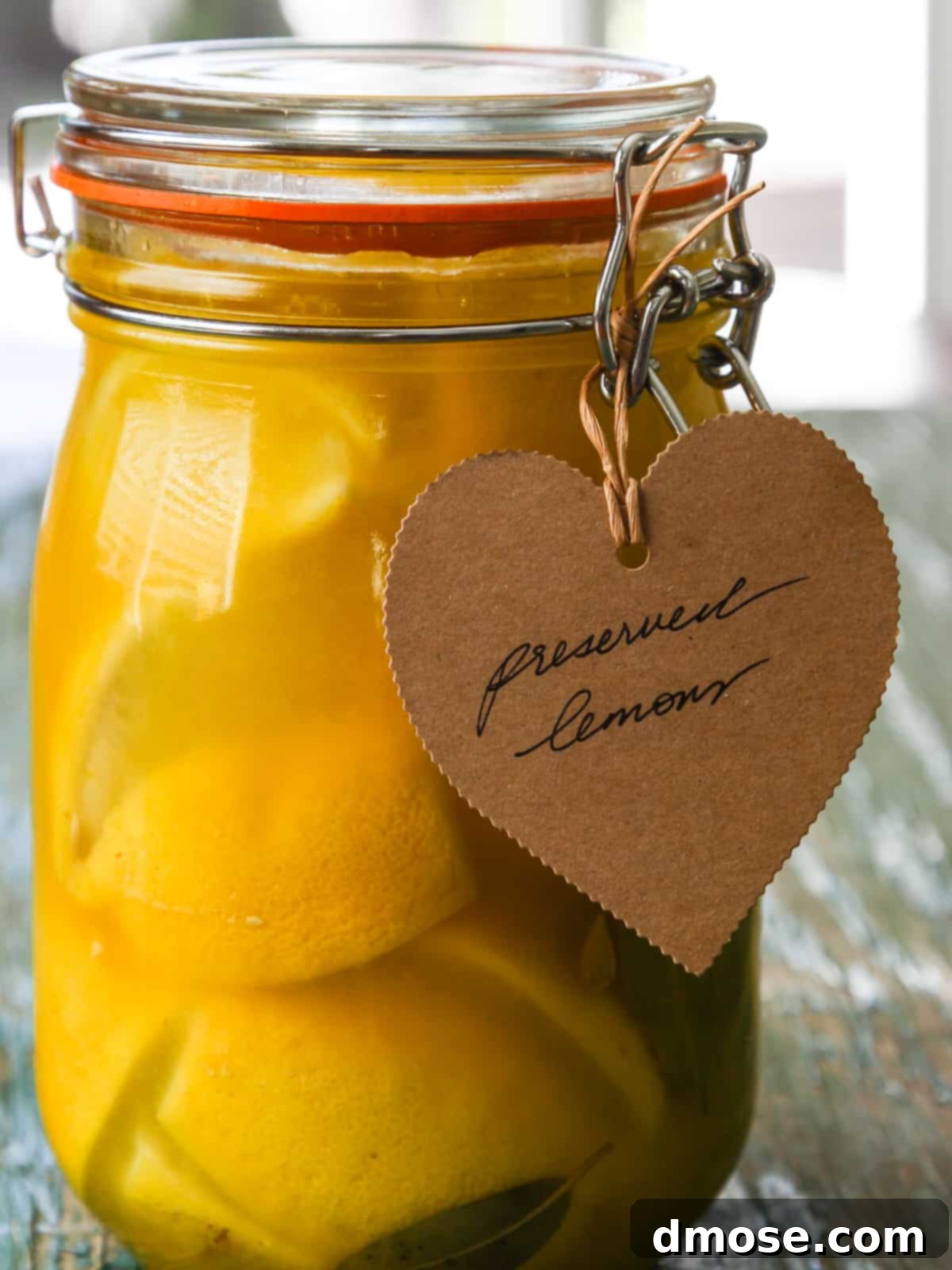 Close up of a jar of preserved lemons with a brown paper tag on it that says preserved lemons.