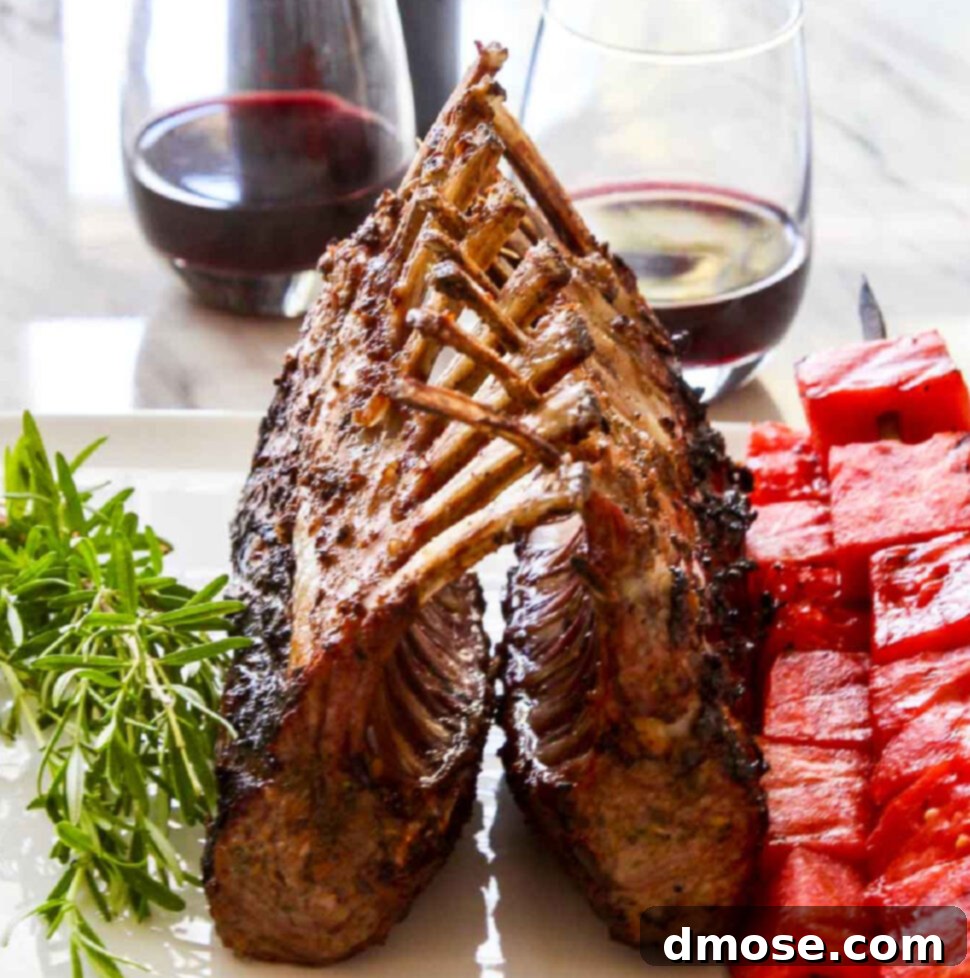 Aromatic Cabernet Rosemary Grilled Lamb Rack 7 A beautiful grilled rack of lamb on a white platter with rosemary sprigs and watermelon skewers.