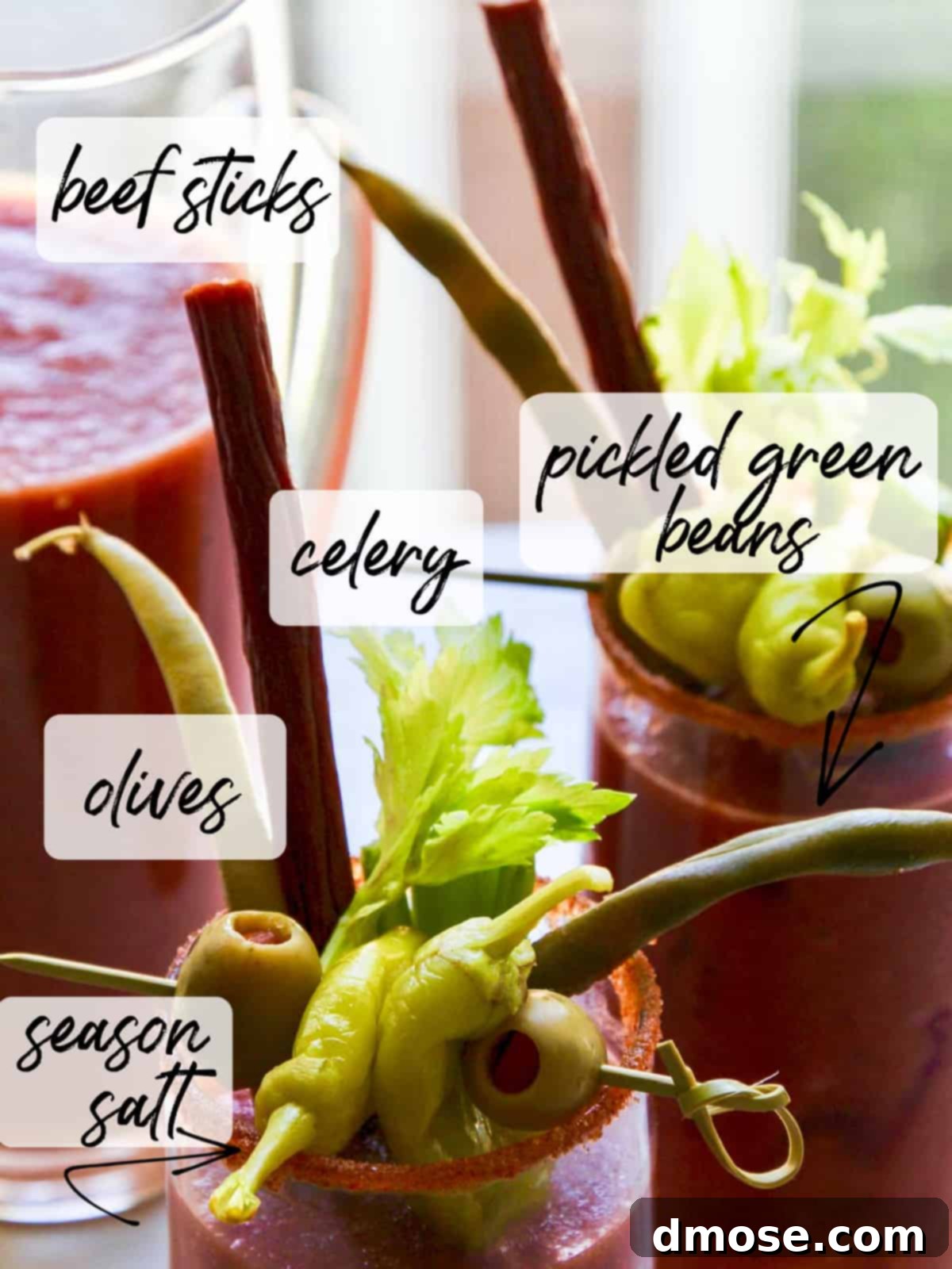 A pitcher of bloody marys with garnish ideas labeled, including pickled green beans.