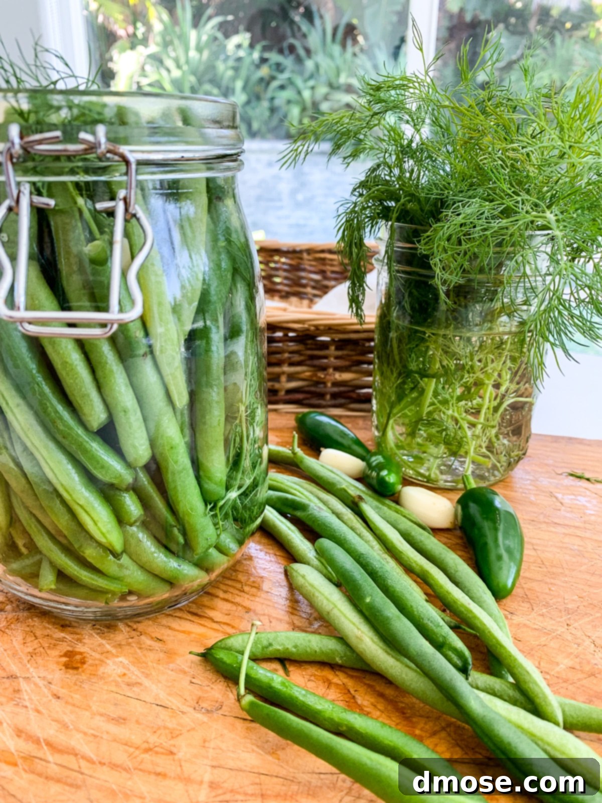 A clear clamp-top jar filled with pickled green beans and ingredients on a cutting board, ready for the brine.