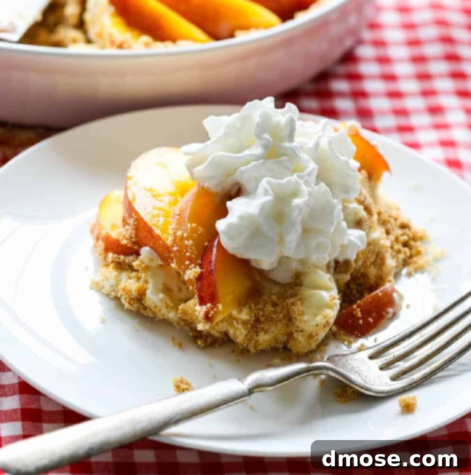 A slice of peach pie on a white plate with a silver fork on a red white check tablecloth.