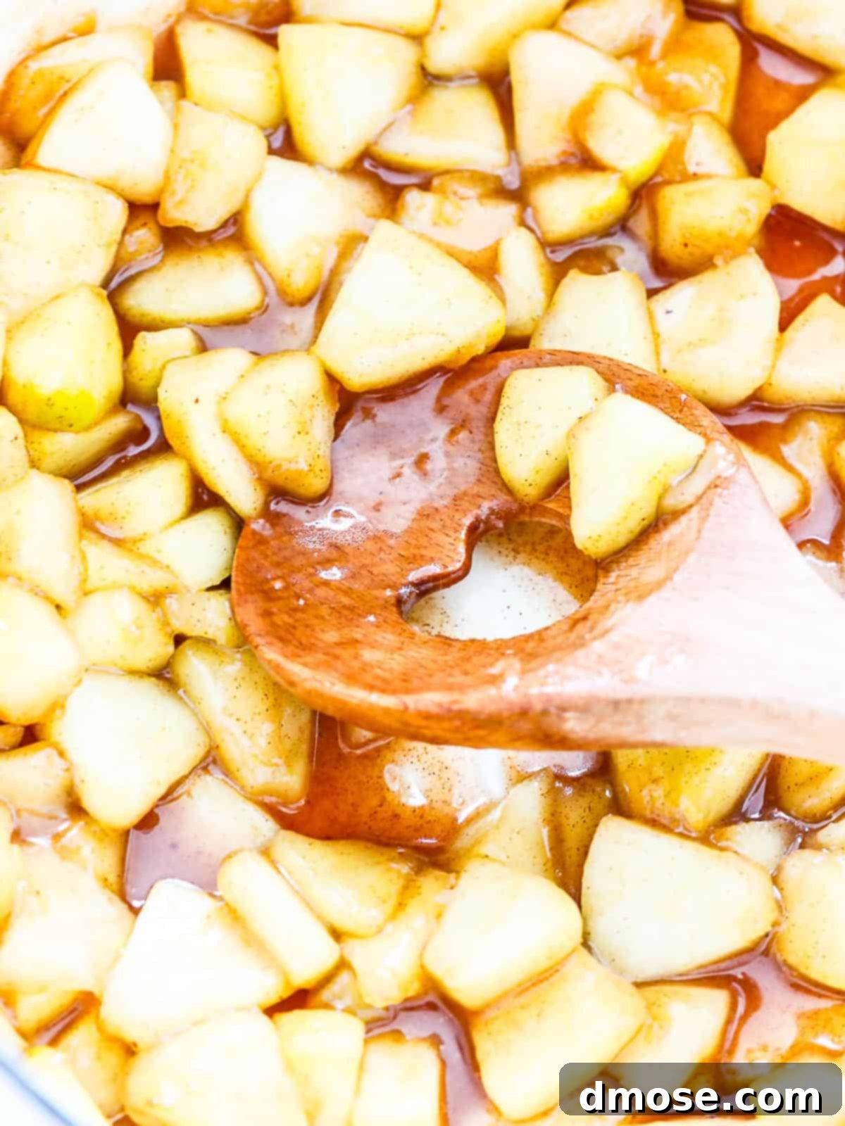 Stirring apple pie filling in a pot on the stovetop.