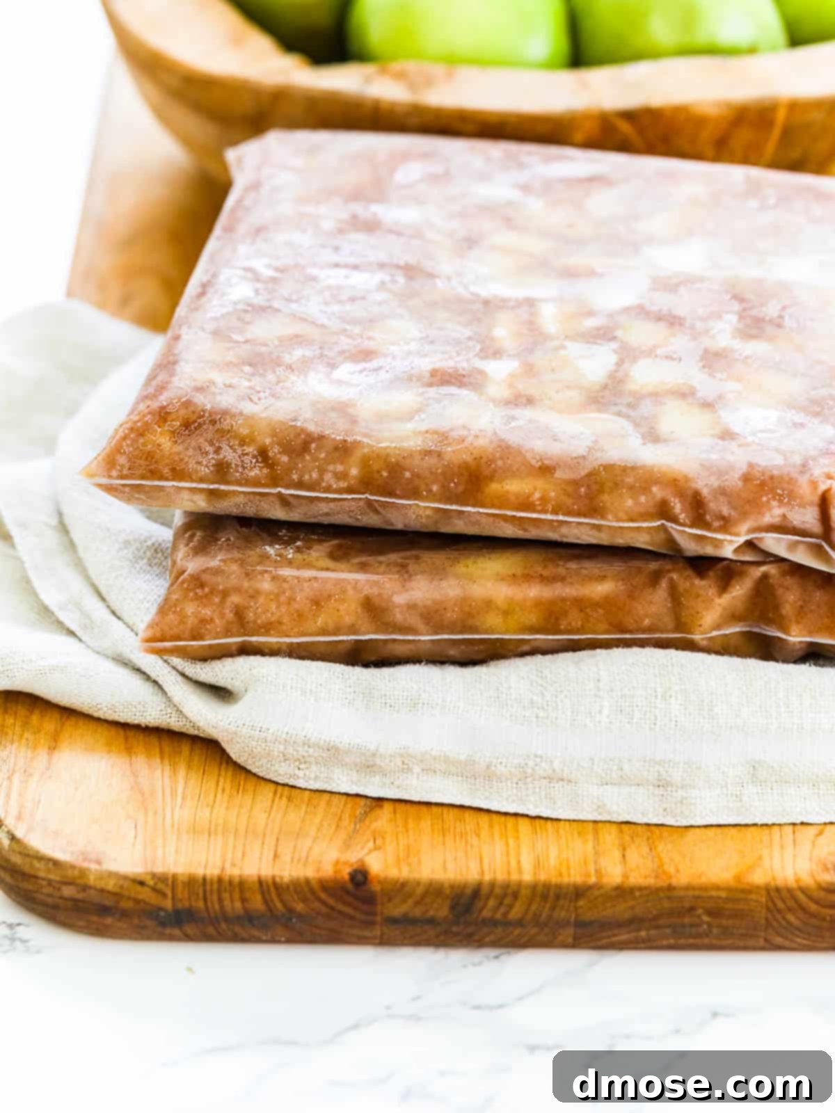 Two zip-top bags filled with frozen apple pie filling, stacked on a tray.