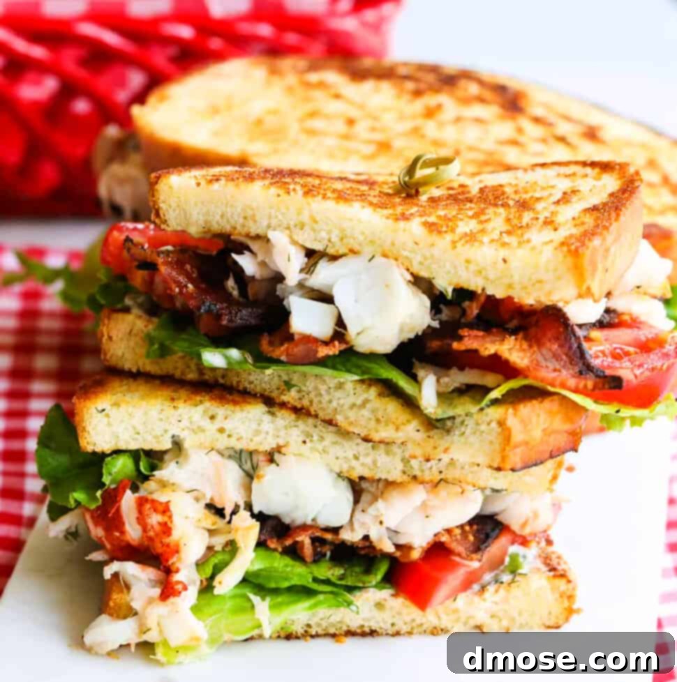 A sliced open BLT lobster sandwich, fully loaded with succulent lobster, crispy bacon, fresh lettuce, and ripe tomato, beautifully stacked on a wooden board, serving as the featured image for the recipe.