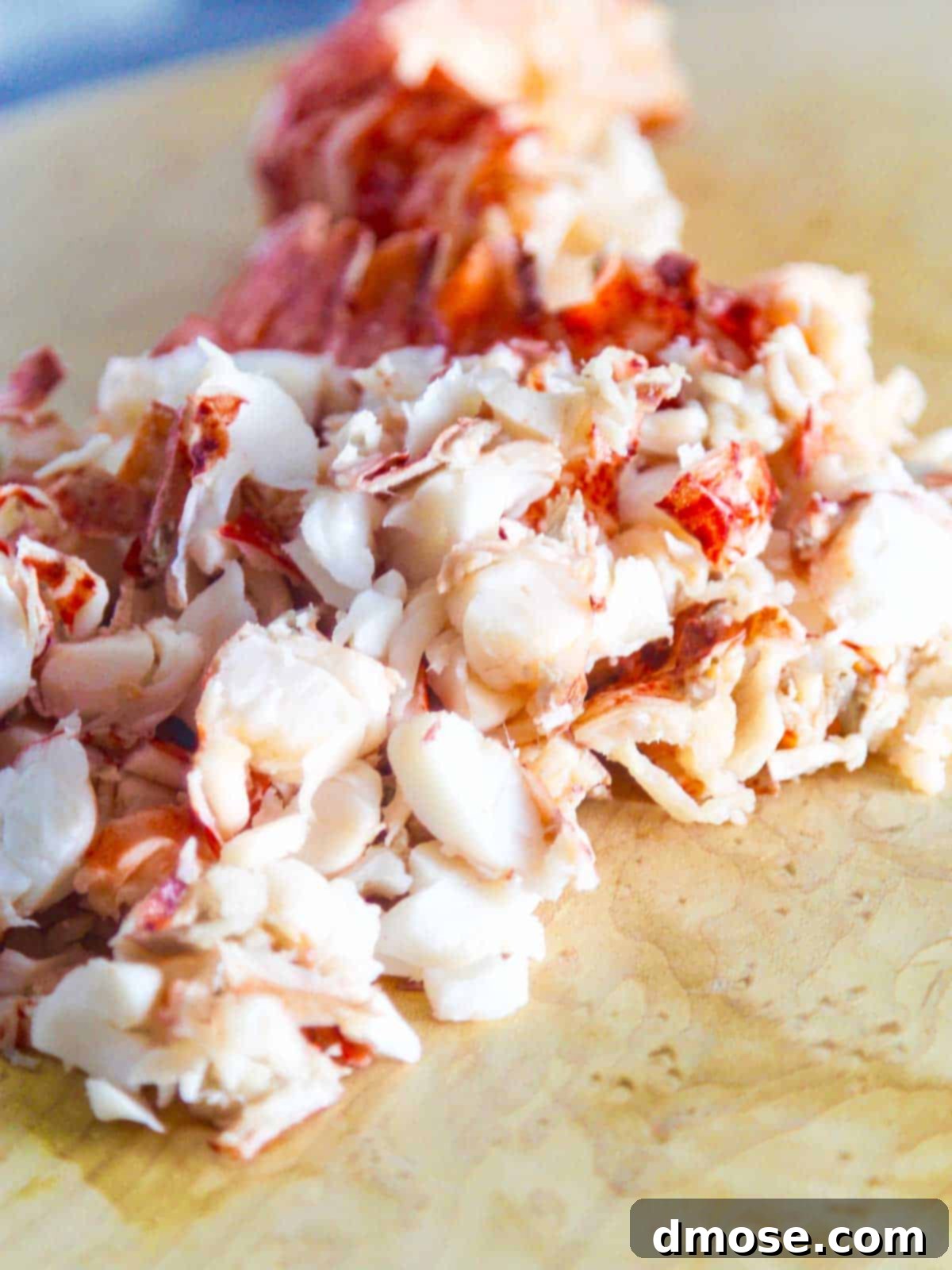A generous pile of freshly cooked lobster meat on a wooden cutting board, meticulously chopped and ready for use in various gourmet recipes.