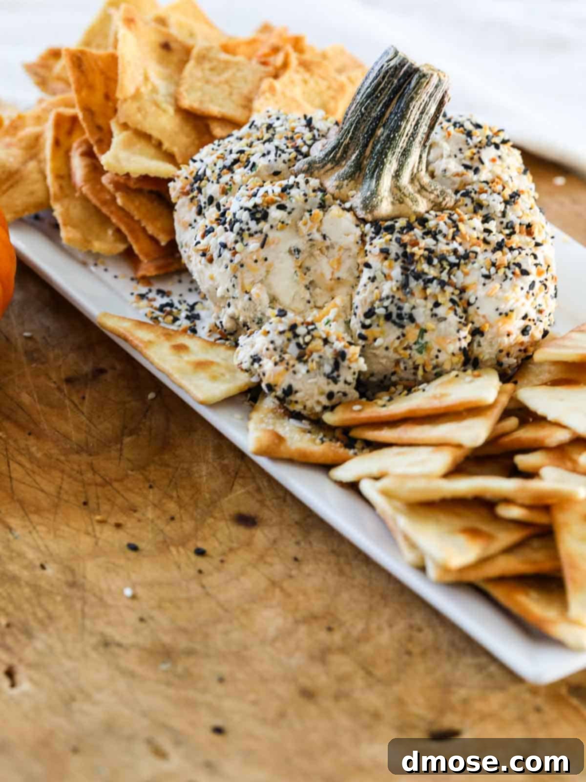 Harvest Everything Bagel Pumpkin Cheese Ball 5 A bite taken out of the Everything Bagel Cheese Ball, showing its creamy interior.