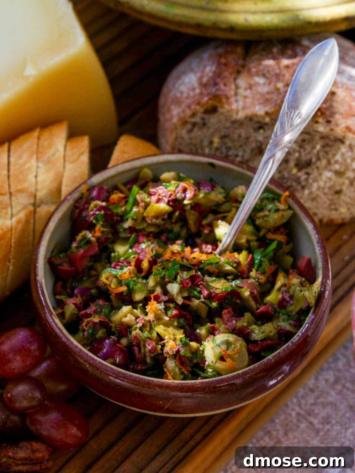 A vintage bowl with vibrant green olive tapenade, accompanied by slices of crusty bread, ready to be served as an appetizer.