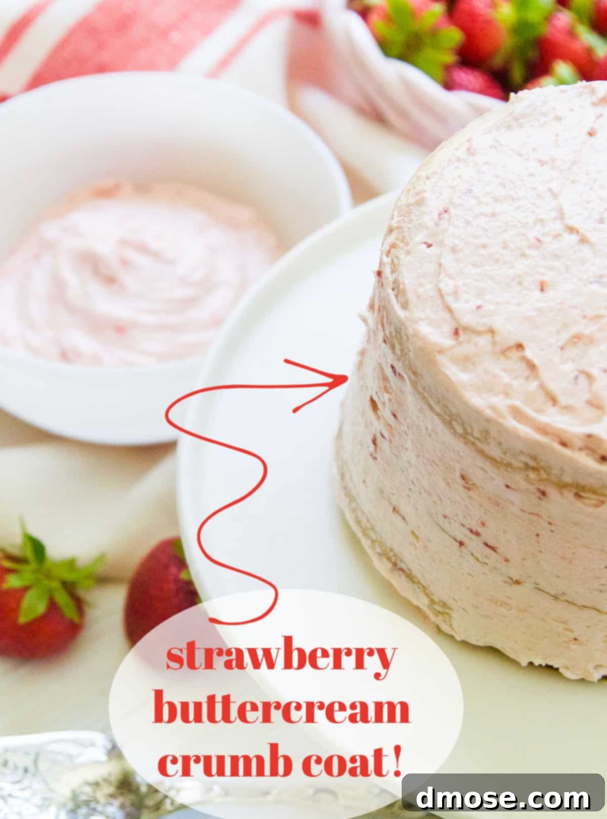 Close-up of a cake being given a crumb coat with strawberry buttercream frosting.