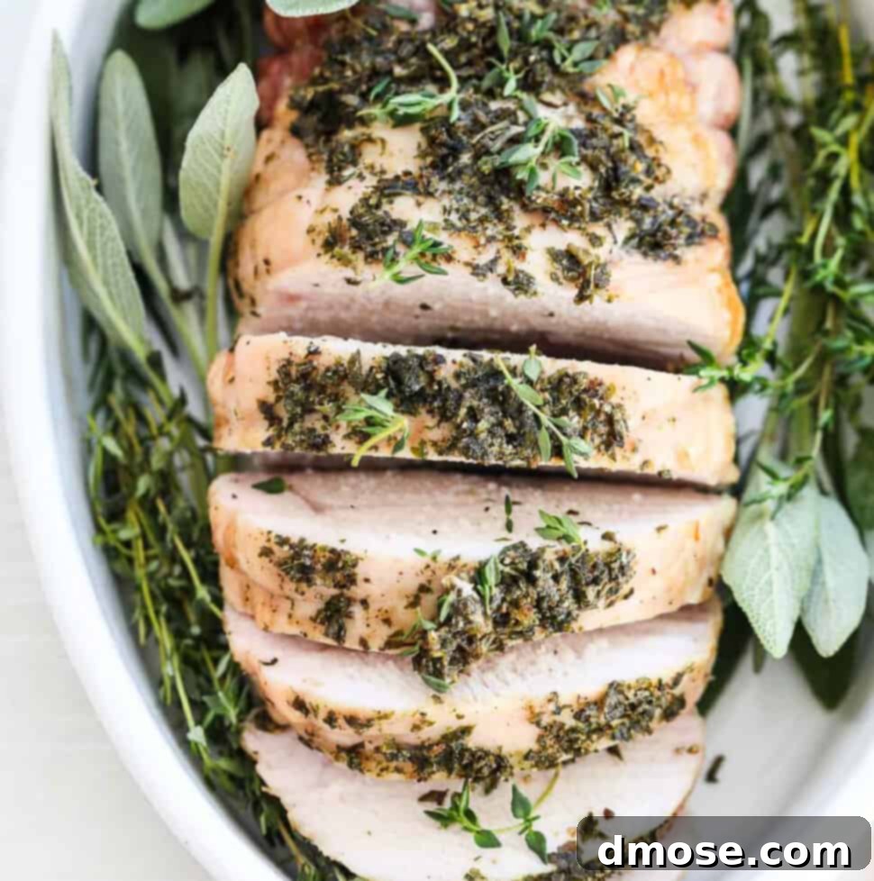 Effortlessly Delicious Turkey Breast 11 Top down view of a roasted turkey breast sliced thick and garnished with fresh herbs.
