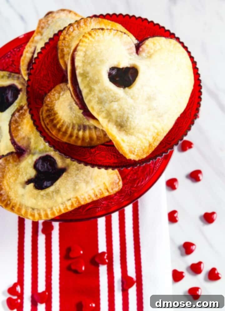 A stack of heart shaped hand pies on red plates with red and white decorations, featuring a crispy sugar crust.