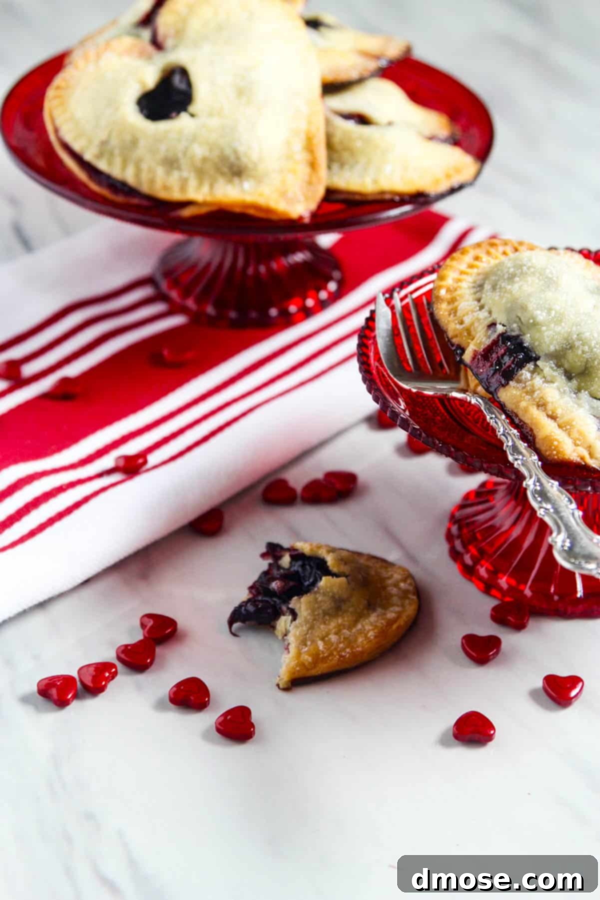 A close-up of a hand holding a chocolate cherry hand pie, showing the flaky crust and rich filling.