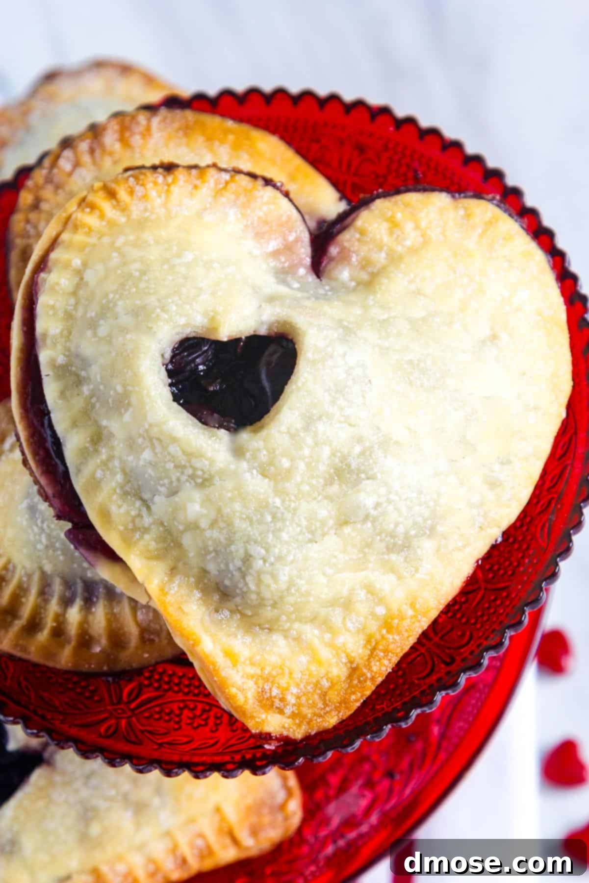 A close-up of a chocolate cherry hand pie on a red plate, showcasing its golden, sugar-crusted exterior and tempting filling.