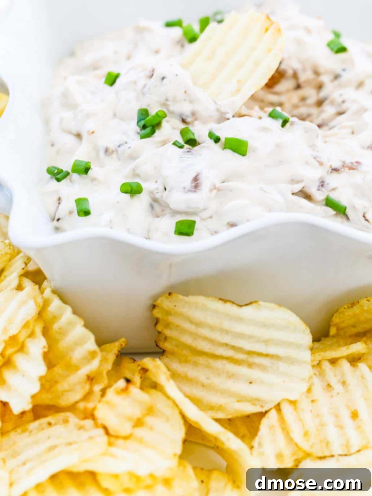 A close-up view of the creamy French Onion Dip in a bowl, with a serving spoon.