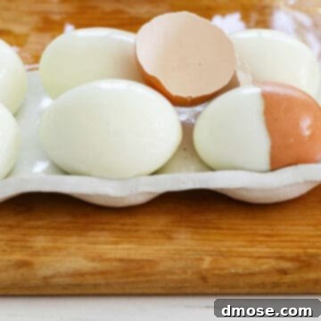 6 perfectly hard boiled eggs with a cracked half of an egg shelf on top.