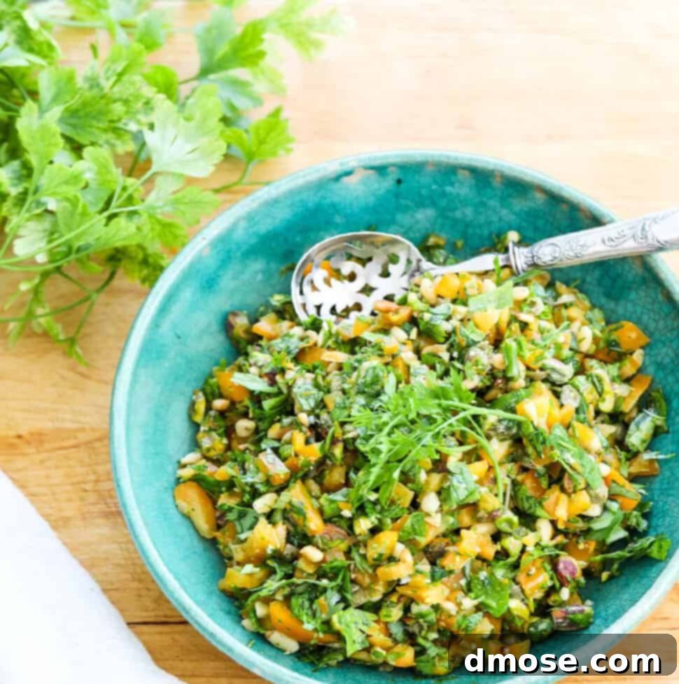A blue vintage bowl filled with vibrant, chopped Gremolata, accompanied by a silver spoon.