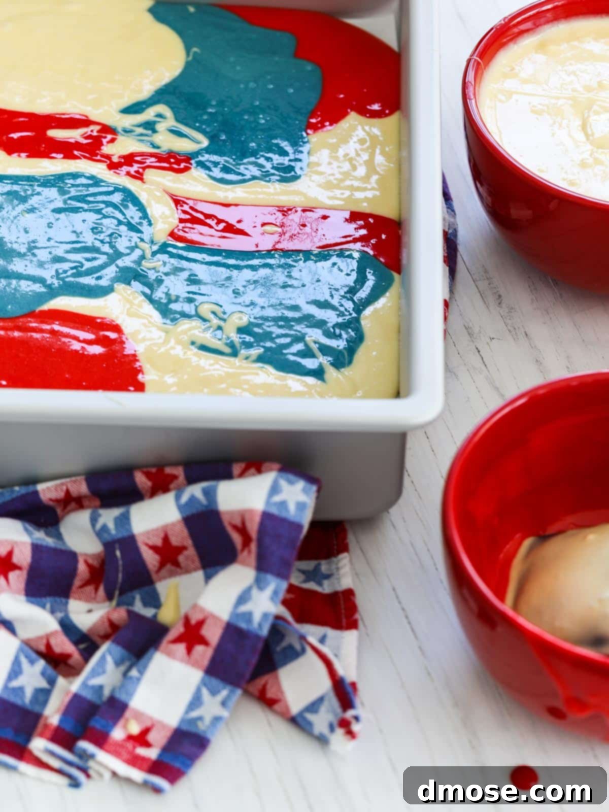 Red, white, and blue cake batter being poured into a pan for an American Flag Cake.