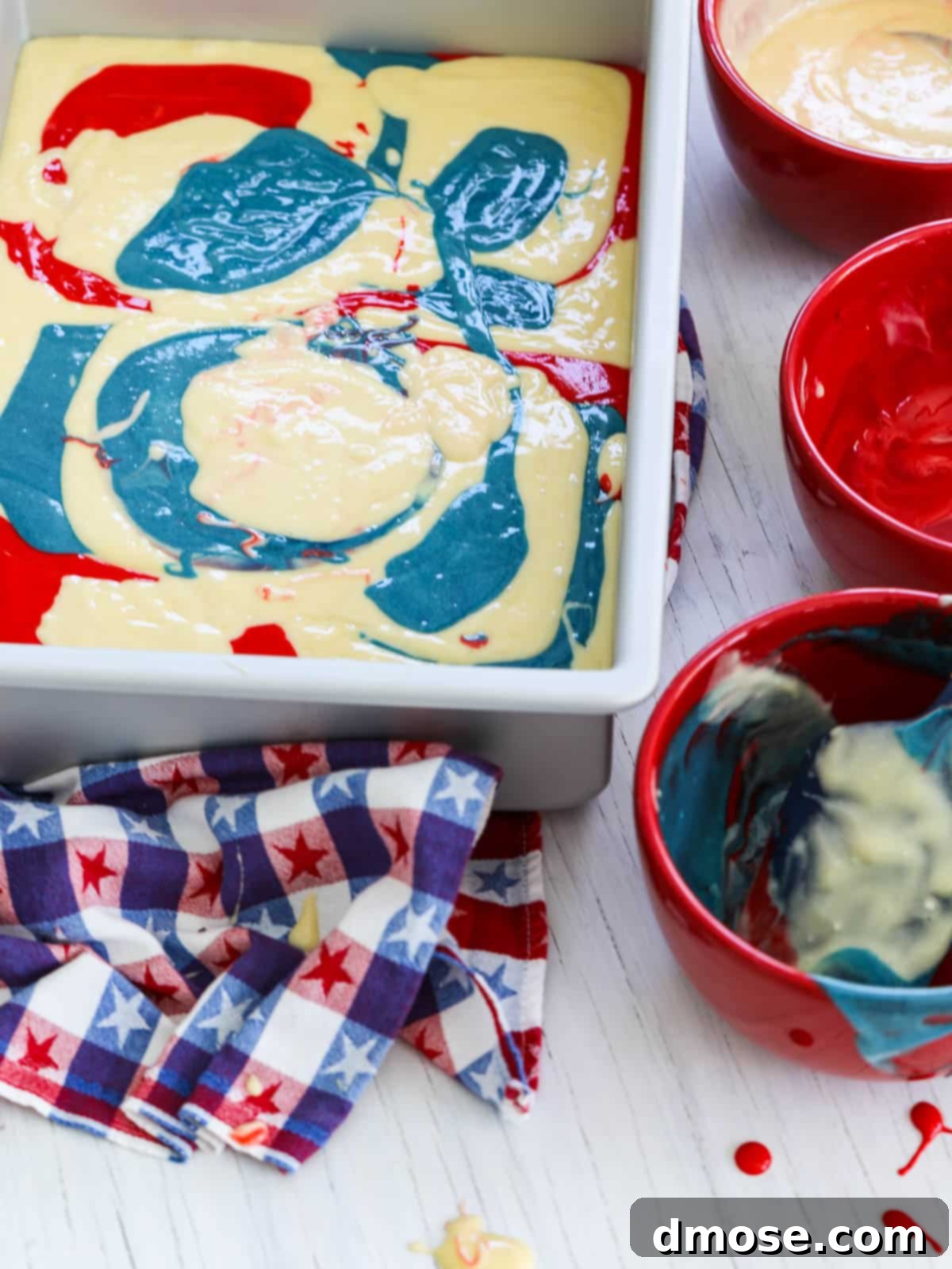 Swirling red, white, and blue cake batter in a pan to create a marbled effect for an American Flag Cake.