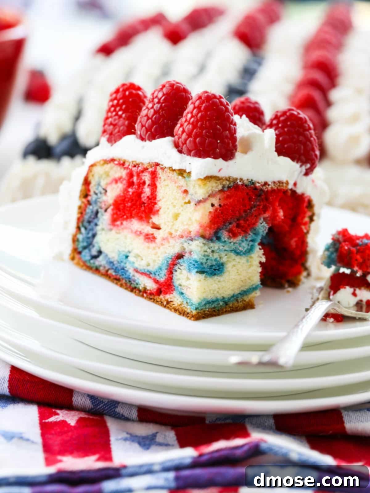 A slice of American Flag Cake showing vibrant red, white, and blue marbled colors, with a fork taking a bite.