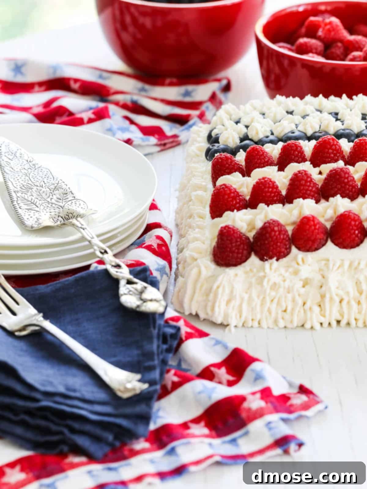Close-up of the corner of a Flag Cake decorated with white frosting, raspberries, and blueberries.