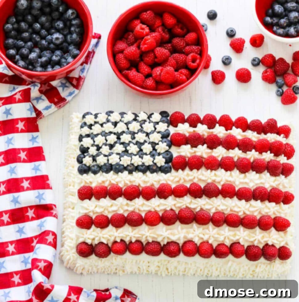 An American flag cake decorated with blueberries, raspberries, and white frosting with a patriotic star towel.