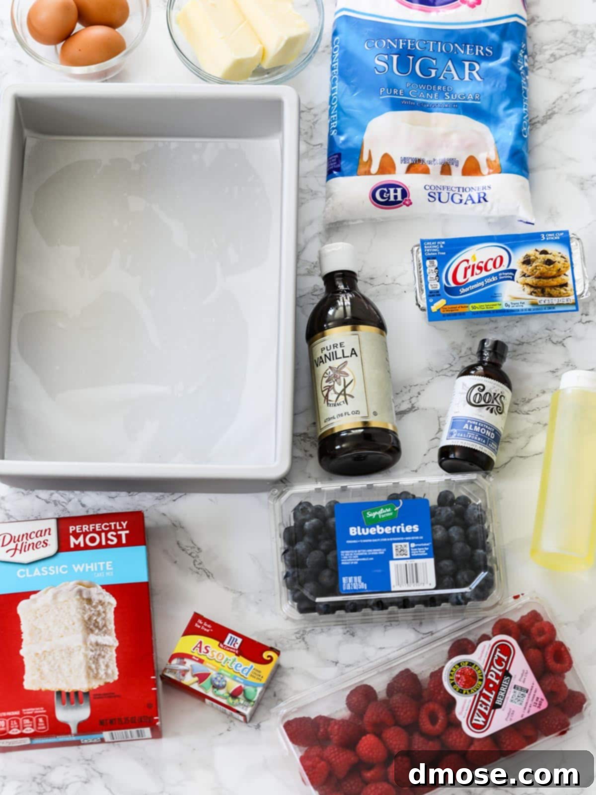 Ingredients for making a July 4th American Flag Cake, including cake mix, food coloring, and berries.