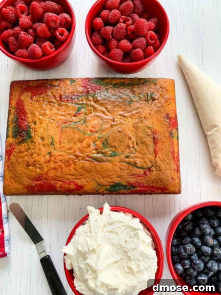 A sheet cake, frosting, and berries laid out for decorating a patriotic cake.