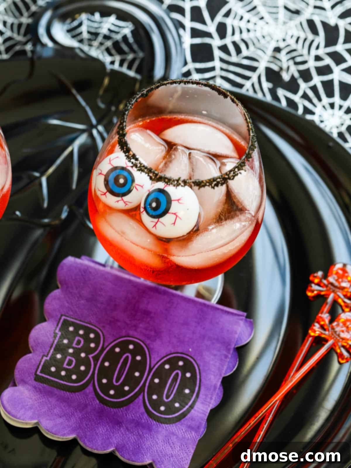 Wicked Aperol Potions 2 A vibrant Halloween Aperol Cocktail with a black sugar rim, ice, and floating eyeballs, ready for a spooky party.