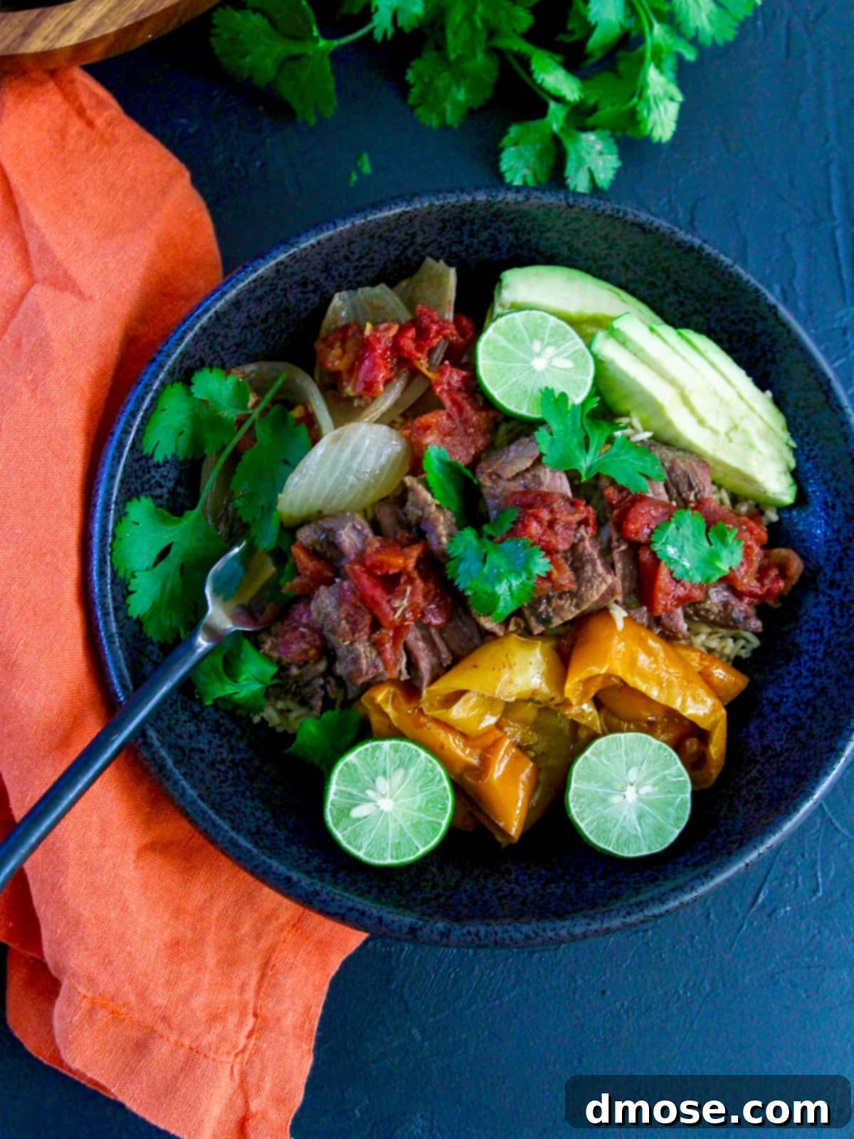 Slow Cooker Fall Apart Beef 6 Shredded beef in a black bowl, garnished with a sprig of cilantro.