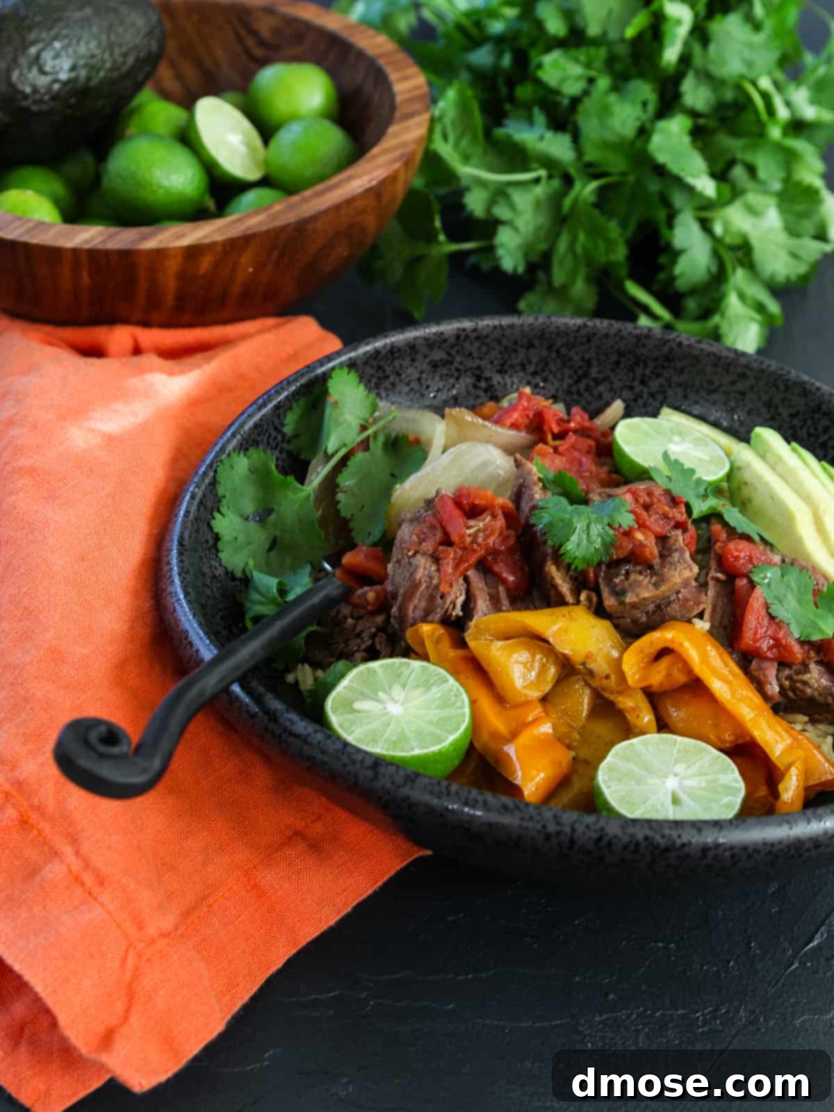 Slow Cooker Fall Apart Beef 7 Shedded beef in a bowl with limes and avocado on the side.