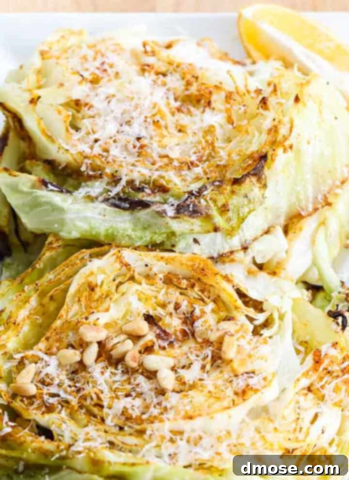 Slow-Cooked Corned Beef Perfection 18 Cabbage steaks on a white rectangle platter garnished with parmesan cheese and toasted pine nuts.