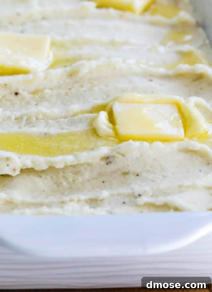 Slow-Cooked Corned Beef Perfection 19 A white casserole dish filled with mashed potatoes and squares of melted butter on top.