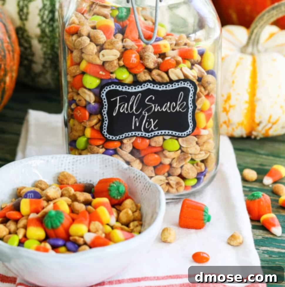 A large glass jar filled with a Fall Snack Mix with candy corn and M&Ms with a small bowl of it nearby.