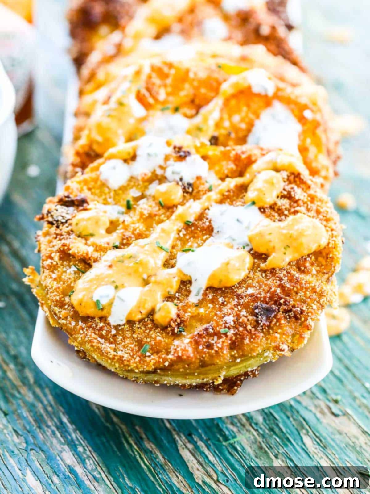 A single fried green tomato slice on a blue and white plate.