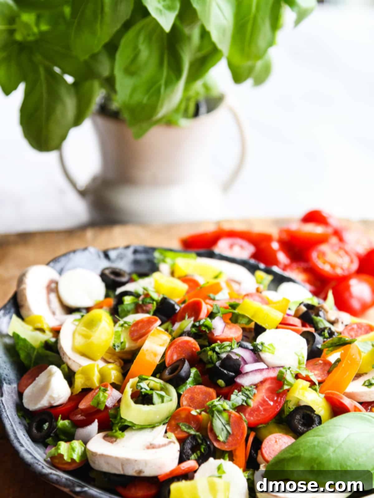 A close-up side view of a bountiful Pizza Salad, showing layers of lettuce, pepperoni, olives, and cheese, ready to be served.