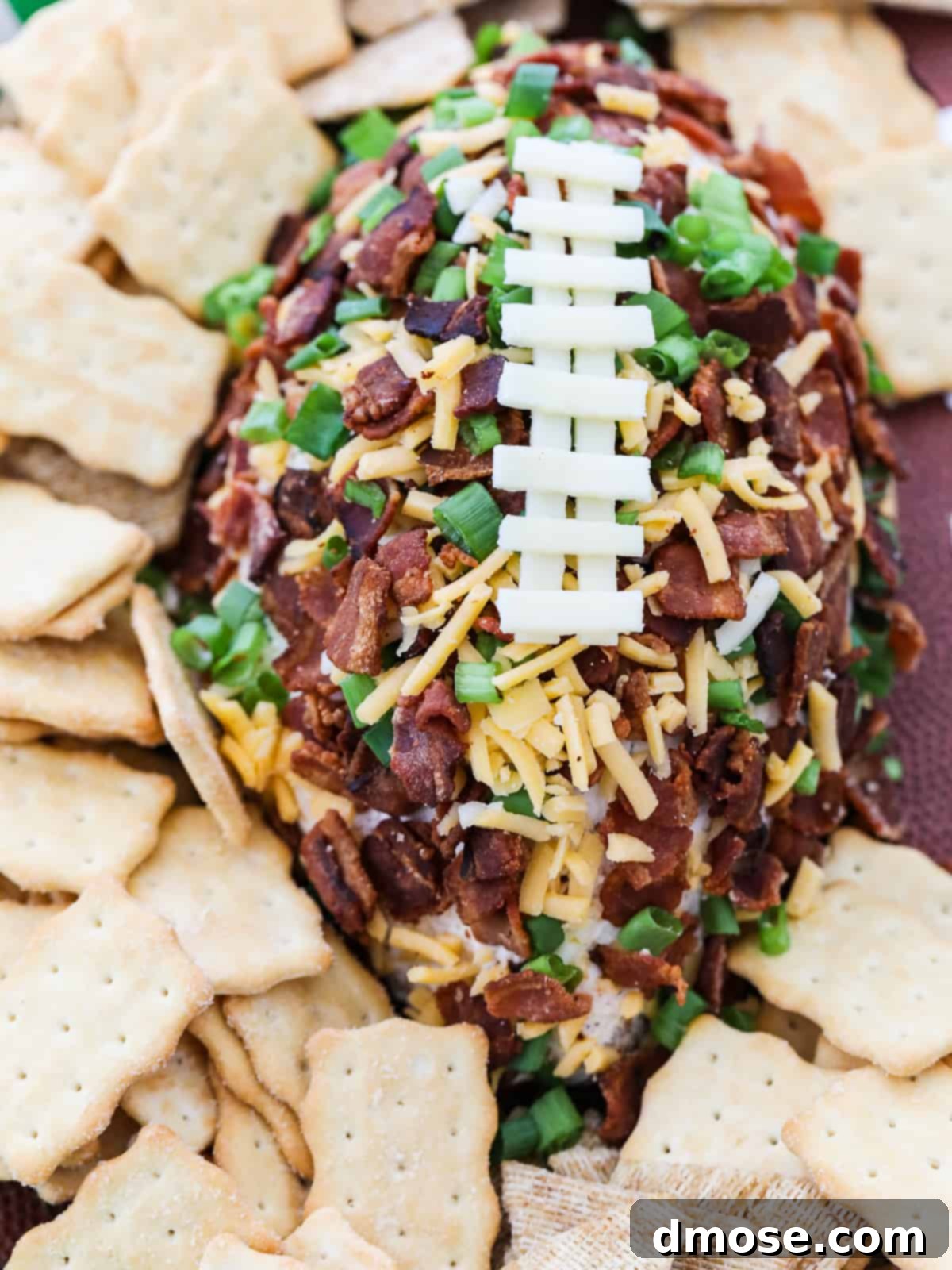 An overhead close-up shot of the football-shaped cheese ball, highlighting its detailed bacon and cheese laces against a festive game day backdrop.