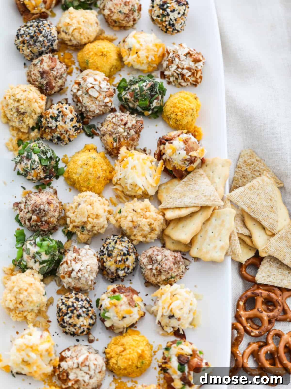 Gourmet Cheese Truffle Bites 2 A platter of assorted mini cheese truffles, some coated in herbs, others in nuts, ready to be served as appetizers.