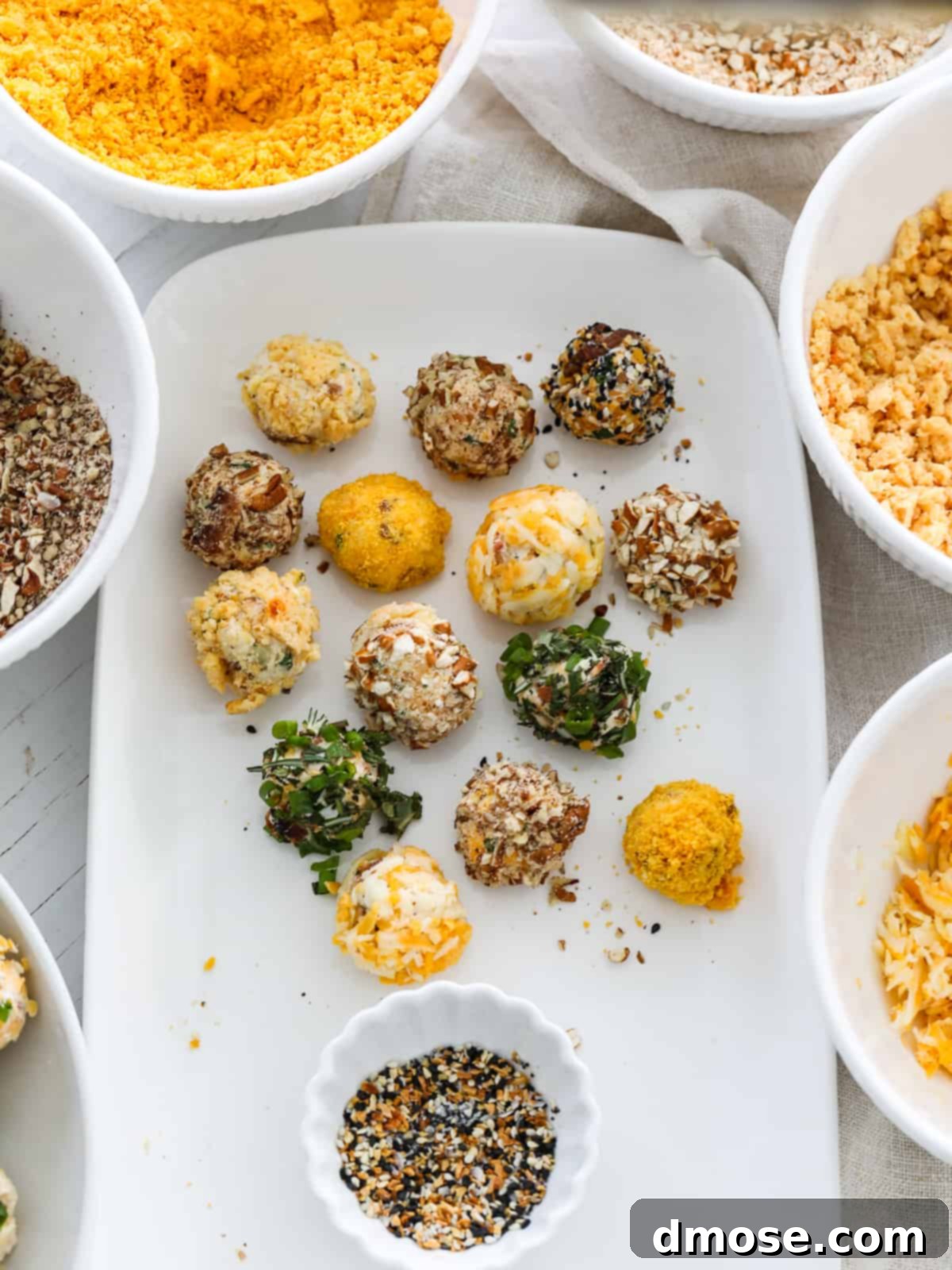 Gourmet Cheese Truffle Bites 11 Close-up view of hands rolling mini cheese truffles into various toppings.