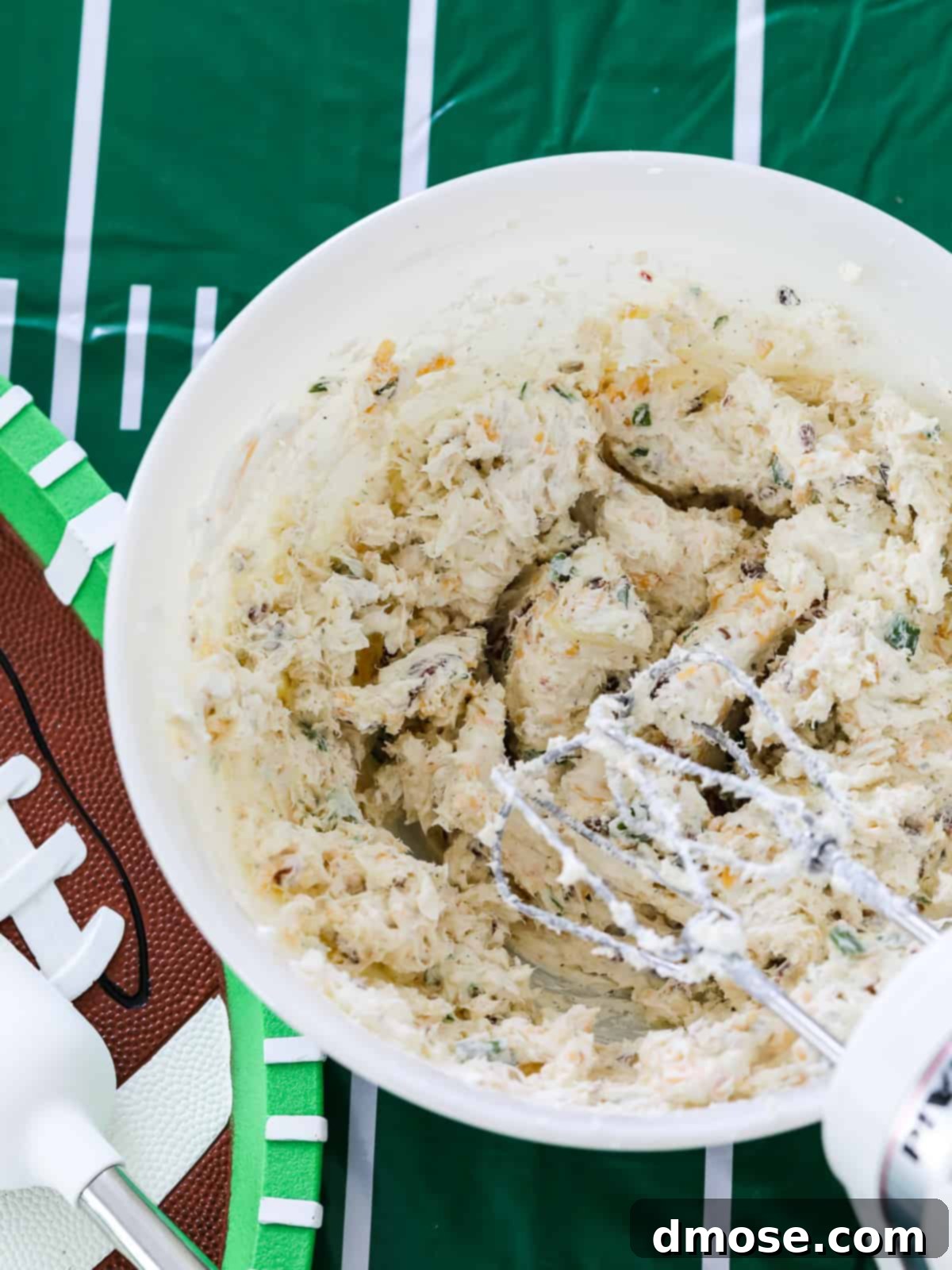 Gourmet Cheese Truffle Bites 8 A bowl of mixed cream cheese, cheddar, pepper jack, bacon, and herbs being stirred.