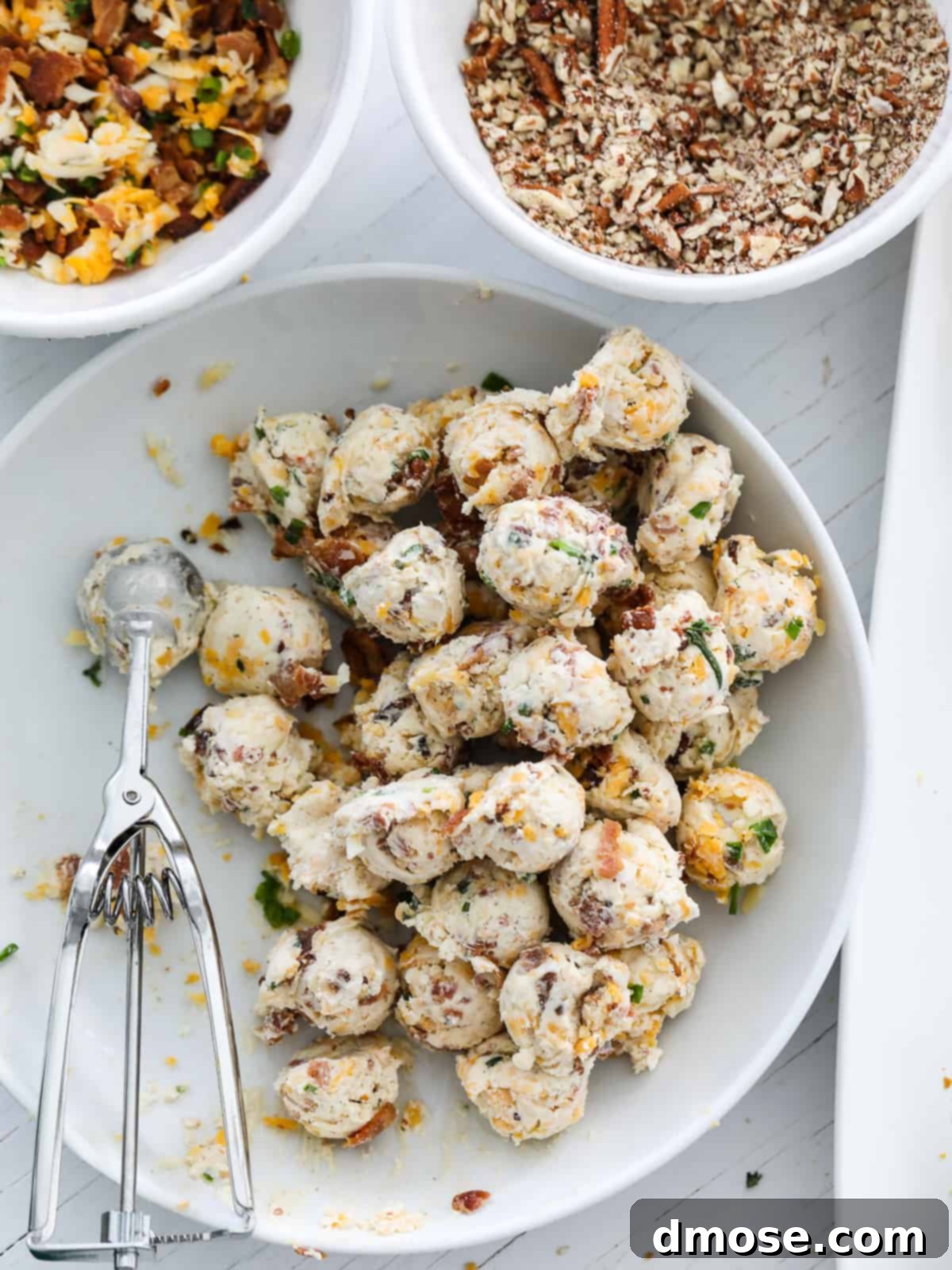 Gourmet Cheese Truffle Bites 9 Hands rolling individual cheese truffles using a scoop on a platter.