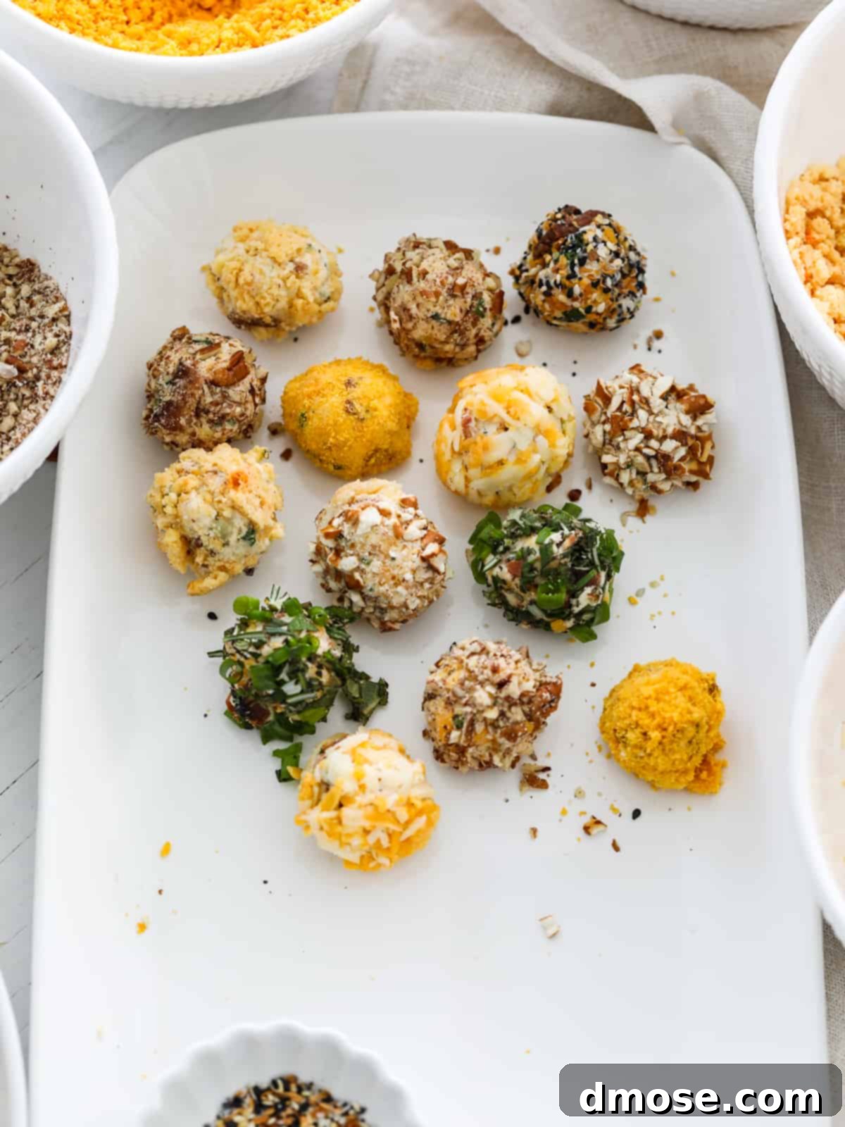 Gourmet Cheese Truffle Bites 10 A platter with several cheese truffles in various stages of being rolled in toppings.