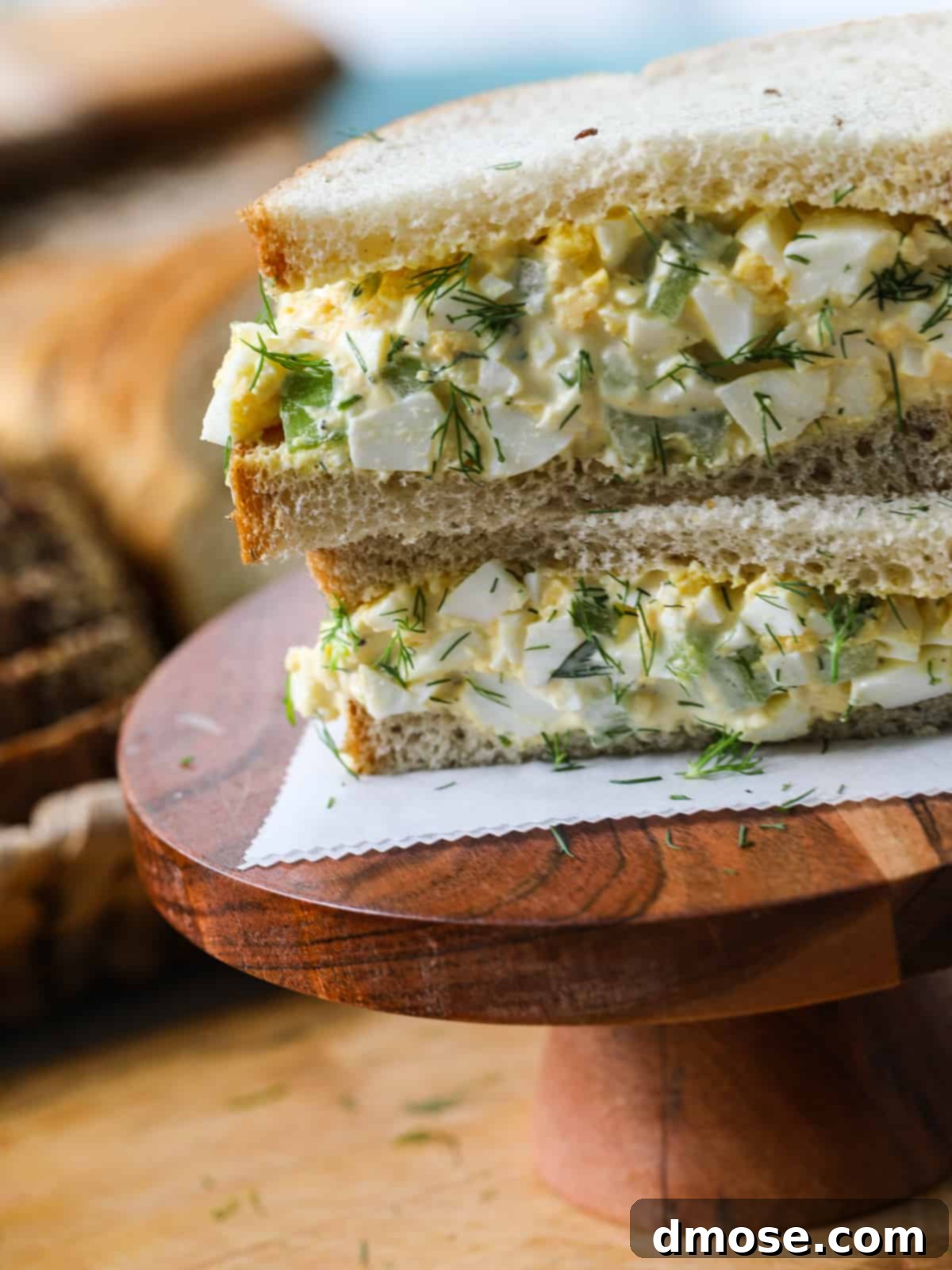 Savory Egg Salad Sensation 15 Close-up of an egg salad sandwich with fresh dill on white bread.