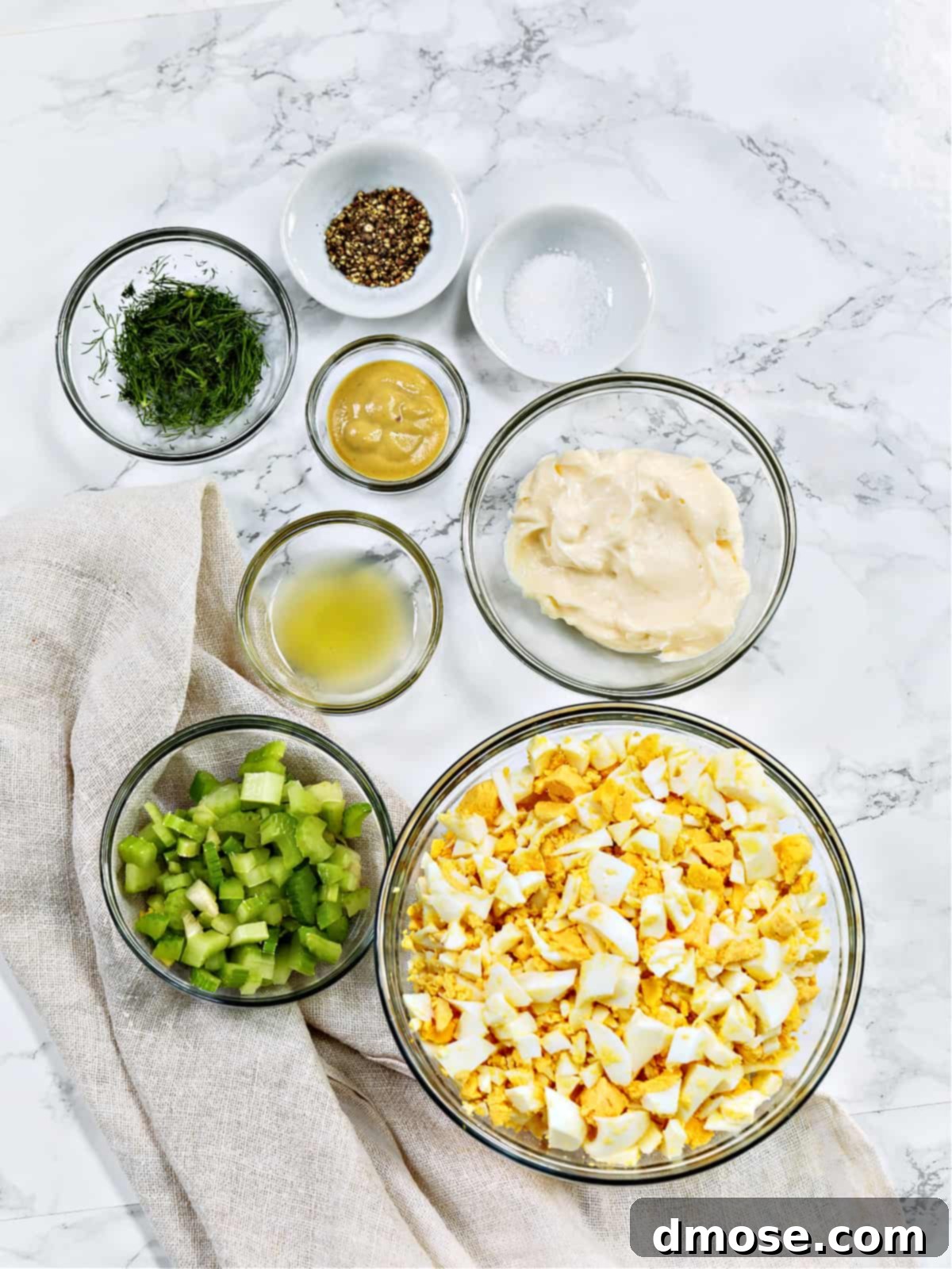 Savory Egg Salad Sensation 3 Assorted egg salad ingredients laid out in bowls on a marble table.