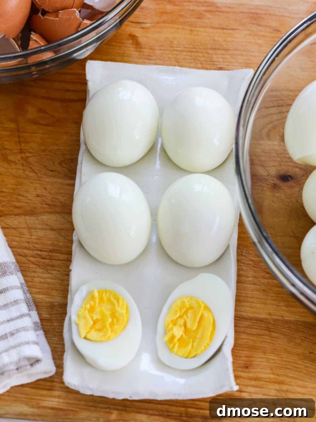 Savory Egg Salad Sensation 4 Looking down on a white ceramic egg dish with hard boiled eggs and one sliced open to reveal the perfectly yellow yolk.