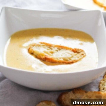 Golden Cheesy Crunch 8 White bowl filled with cheese soup and a homemade crouton on top.