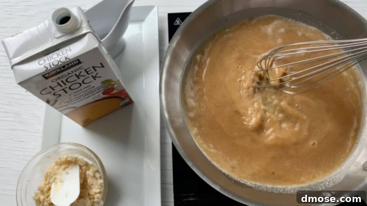 Savory Turkey Gravy 9 Close-up of turkey gravy simmering gently in a saucepan, being stirred with a wooden spoon.