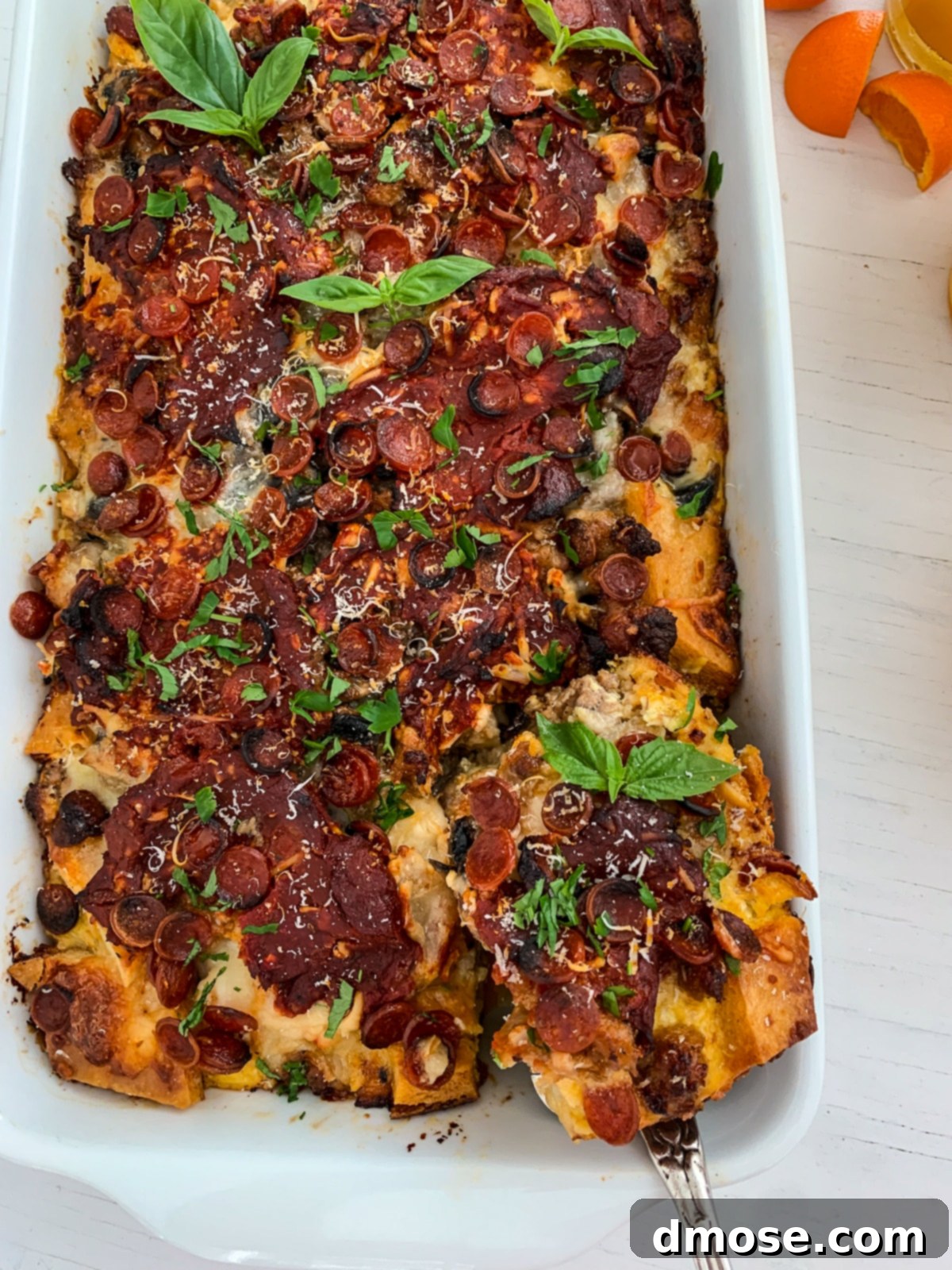 Cheesy Pizza Breakfast Bake 12 A serving utensil lifting a slice of pizza breakfast casserole from the baking dish.