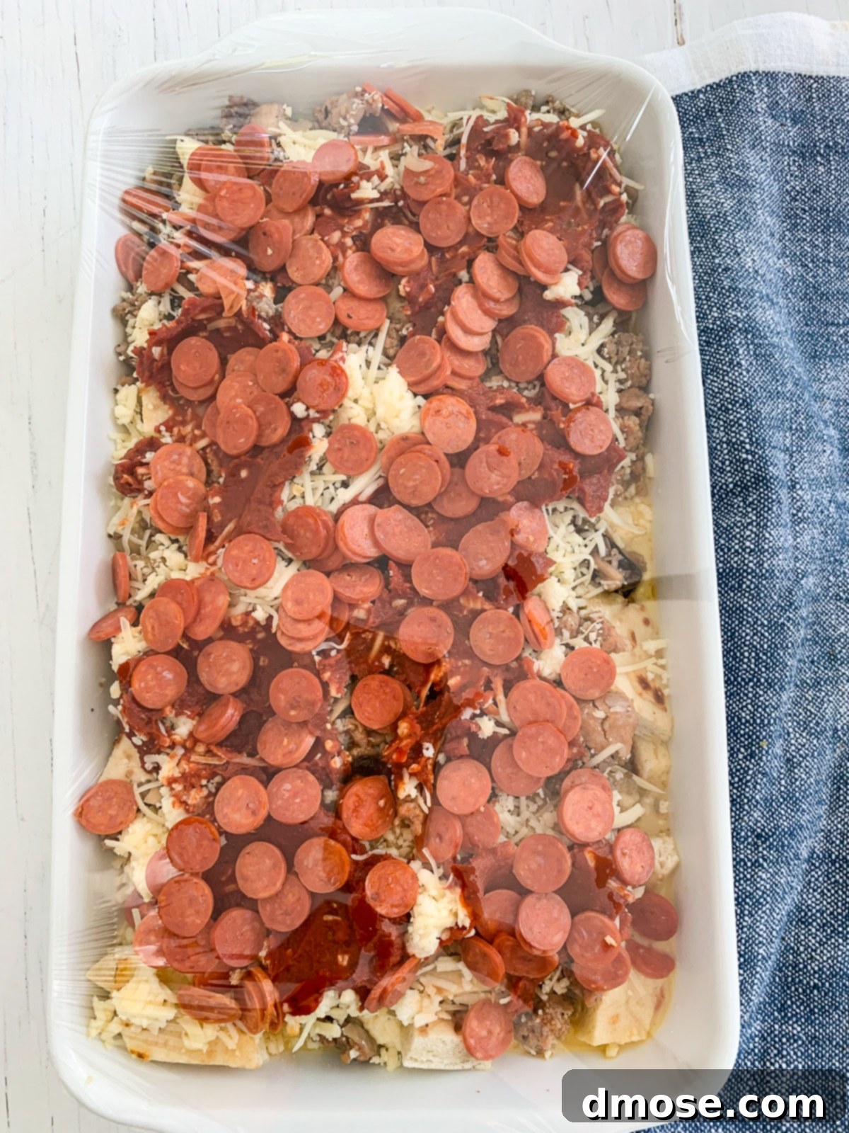 Cheesy Pizza Breakfast Bake 14 Breakfast casserole covered with plastic wrap, prepared for overnight refrigeration.