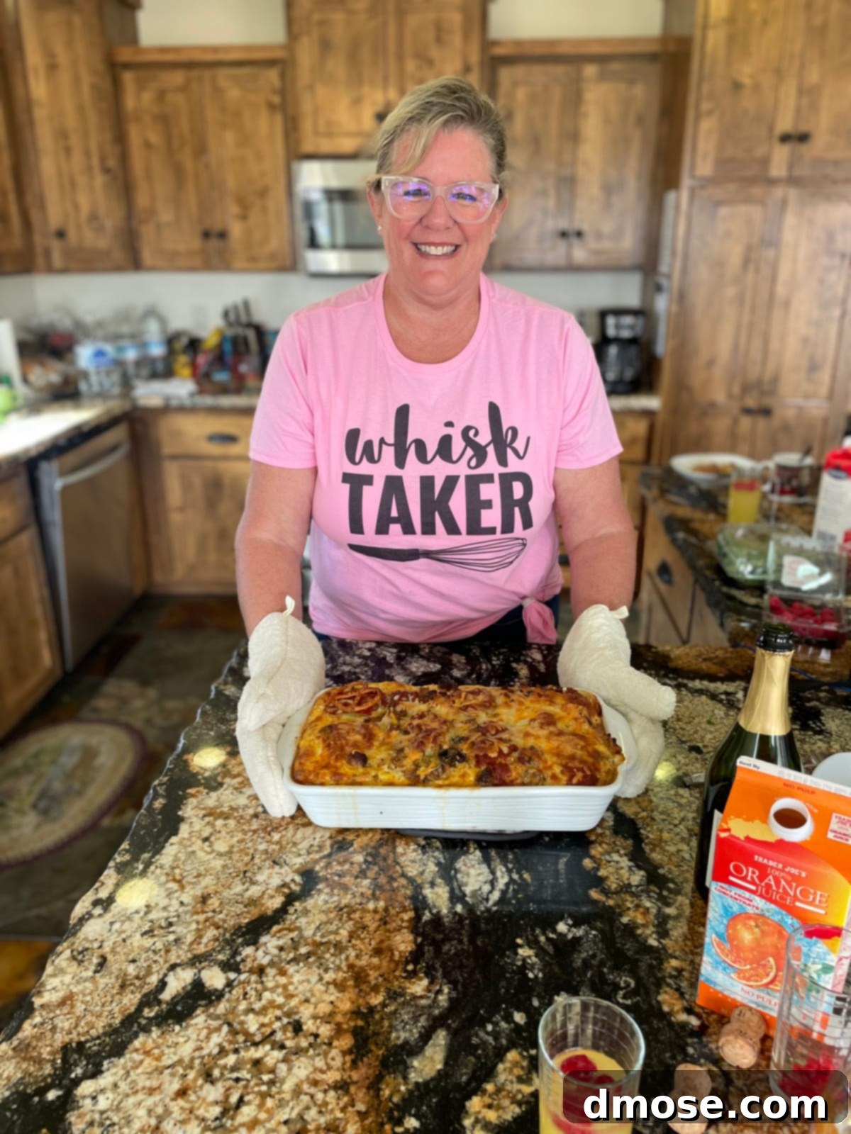 Cheesy Pizza Breakfast Bake 18 A lady in a kitchen holding a breakfast casserole with oven mitts, smiling and about to serve brunch.