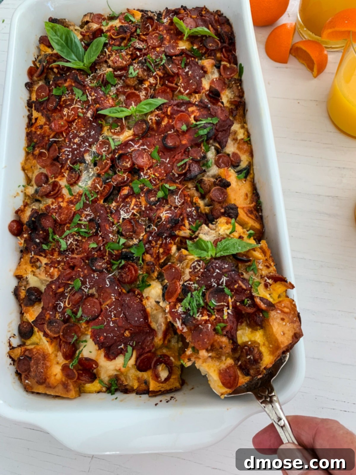 Cheesy Pizza Breakfast Bake 4 A hand lifting a perfect slice of pizza breakfast casserole from the baking dish.